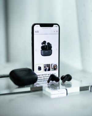 Close-up of a smartphone displaying wireless earbuds details, surrounded by sleek earbuds and a case.